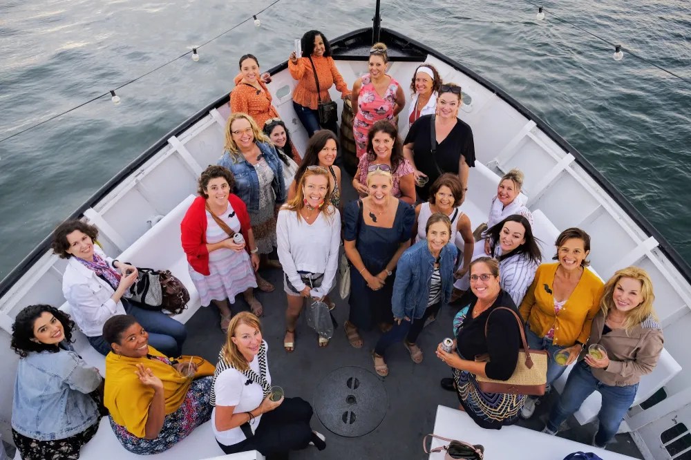 Group of 21 people standing on a boat deck, posing and smiling for a photo.