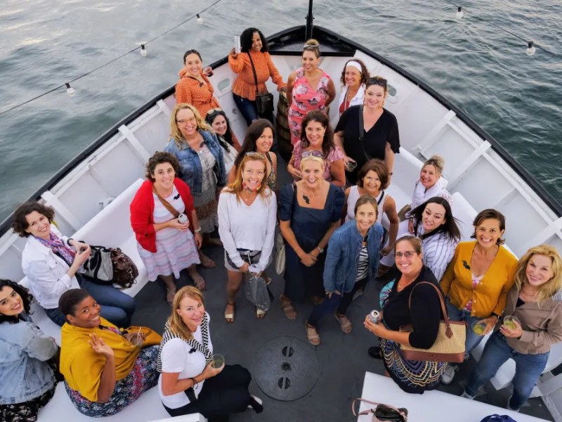 Group of women smiling on a boat deck with water in the background.