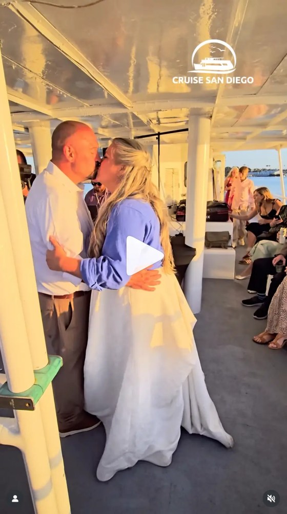 Couple kissing on a boat with passengers seated in the background.