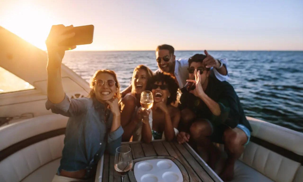Unconventional celebrations on the water San Diego Group of friends taking a selfie on a boat at sunset.