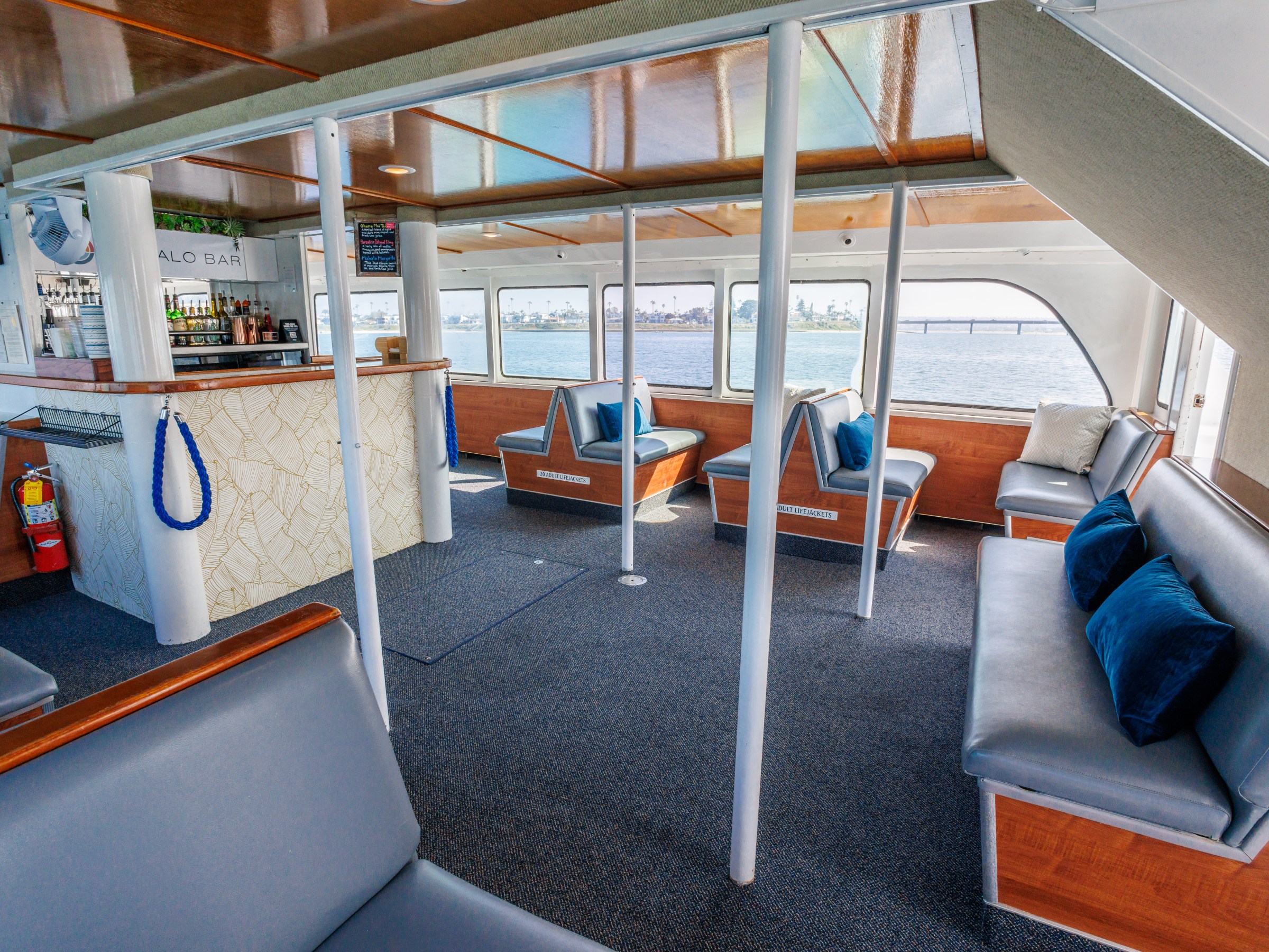 Spacious boat interior with lounge seating and a small bar.