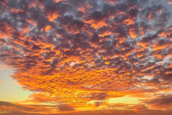 Sunset over ocean with vibrant orange and purple clouds.